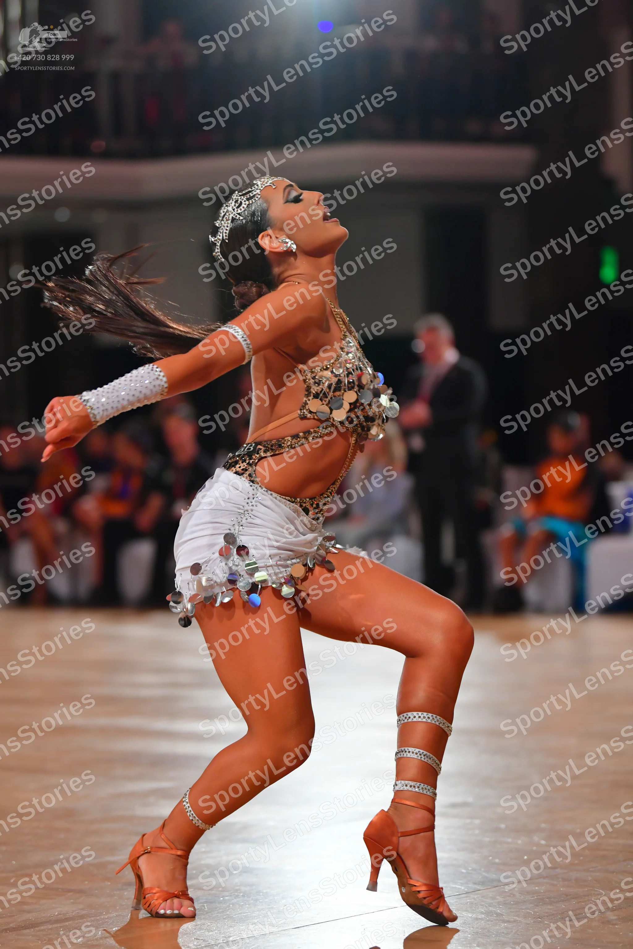 Dancesport competitor: Female dancer: white and tan Latin dance costume embellished with large silver m
