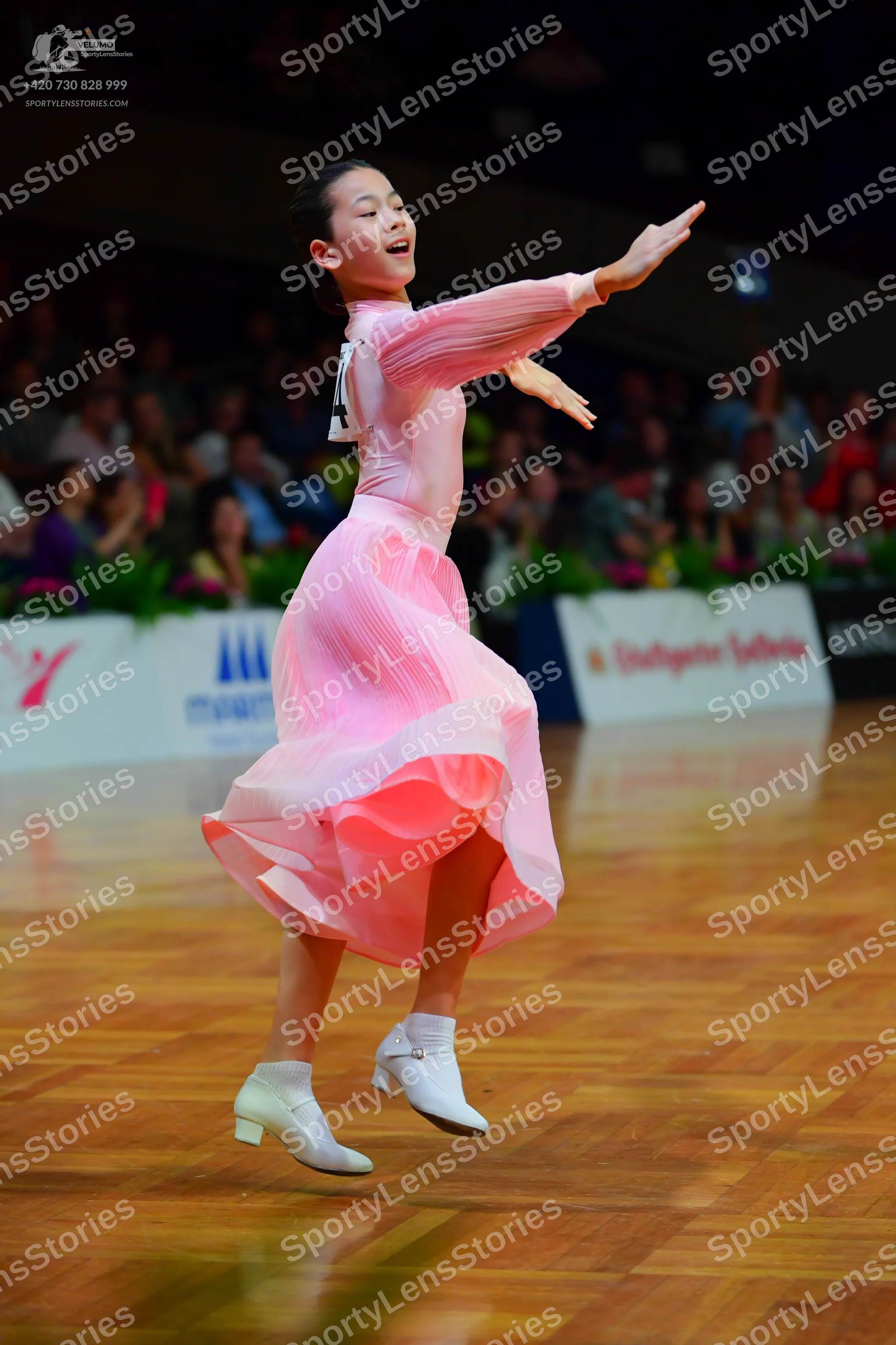 Dancesport competitor: Female dancer: pink long-sleeved ballroom dress with a flowing skirt and white d