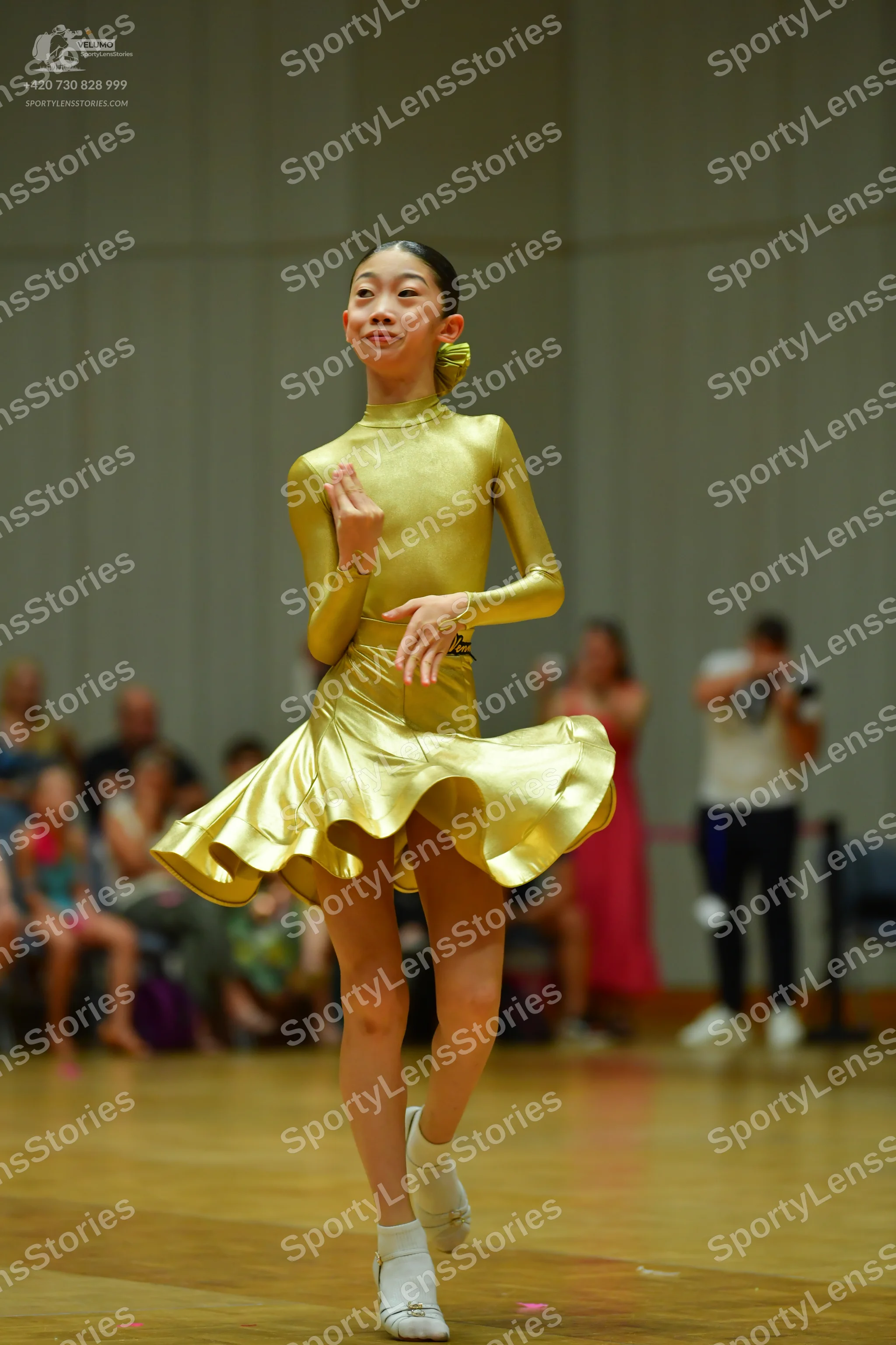 Dancesport competitor: Female dancer: gold-colored, long-sleeved, high-necked dress with a short, flare