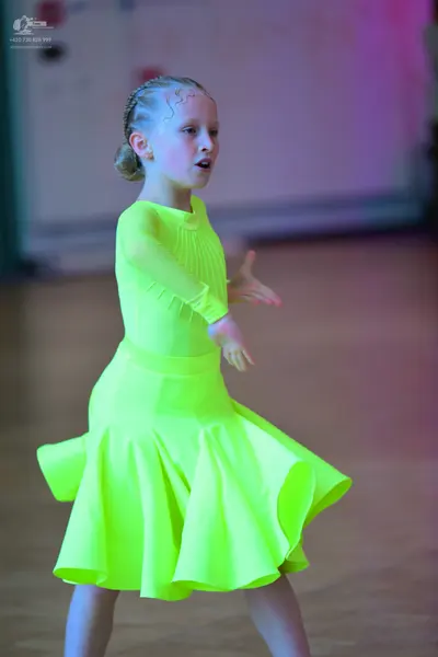 Dancesport competitor: Female dancer: neon yellow long-sleeved latin dress with a flared skirt