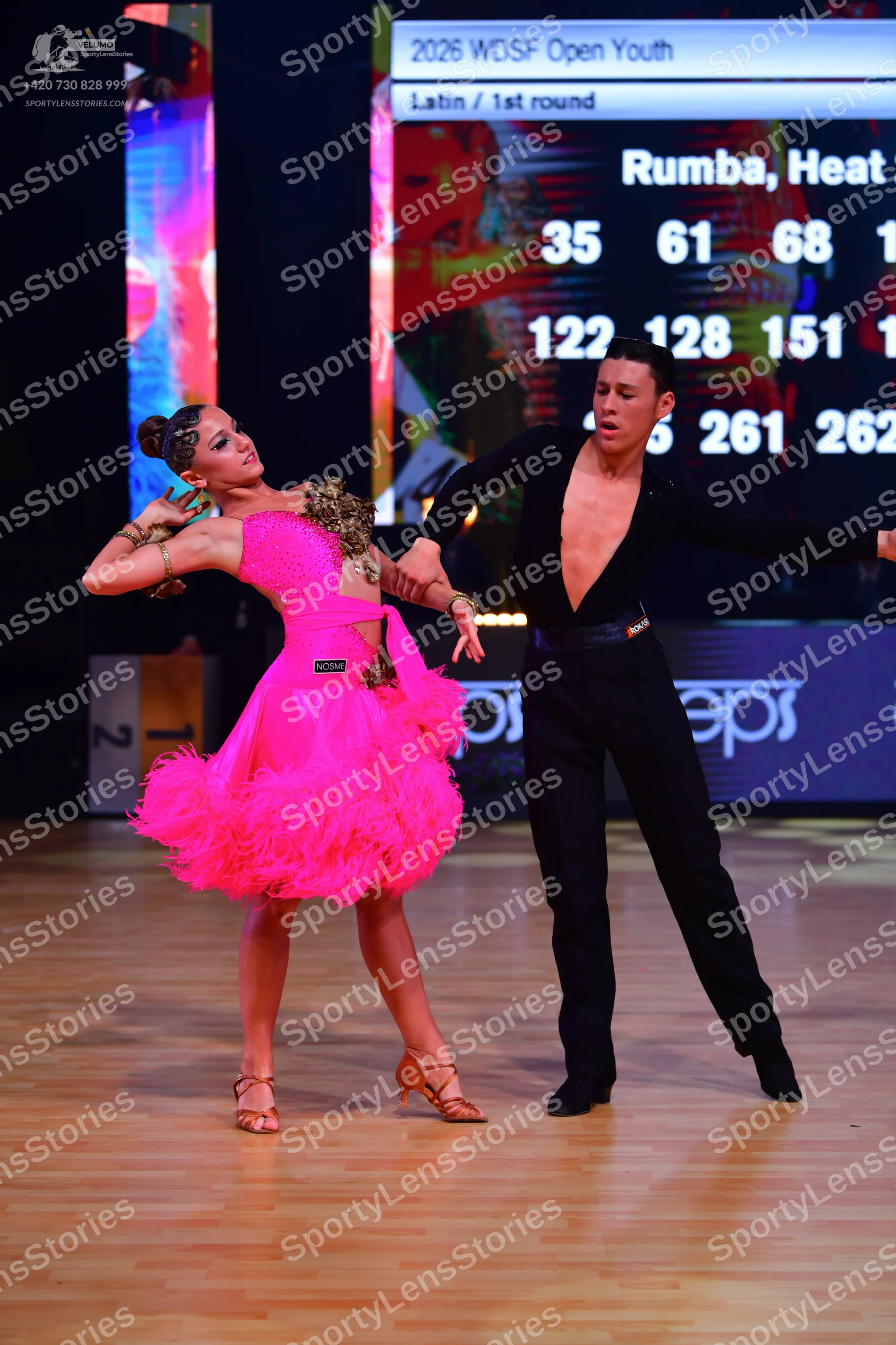 Dancesport competitor: Female dancer: bright pink Latin dress with a layered, ruffled skirt and gold an
