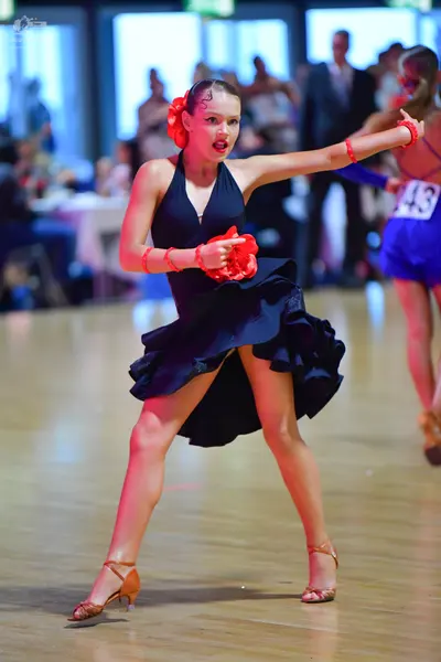 Dancesport competitor #43: Female dancer 1: black latin dress with a ruffled skirt, red flower in hair, and