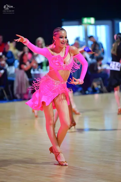 Dancesport competitor #214: Female dancer: bright pink Latin dance dress with sequins, cutouts, and long fri