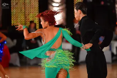 Dancesport competitor: Female dancer: teal latin dress with fringe, a long sleeve, and sequin embellish