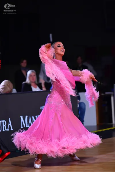 Dancesport competitor: Female dancer: pink ballroom gown with pink feather trim on the sleeves and hem,