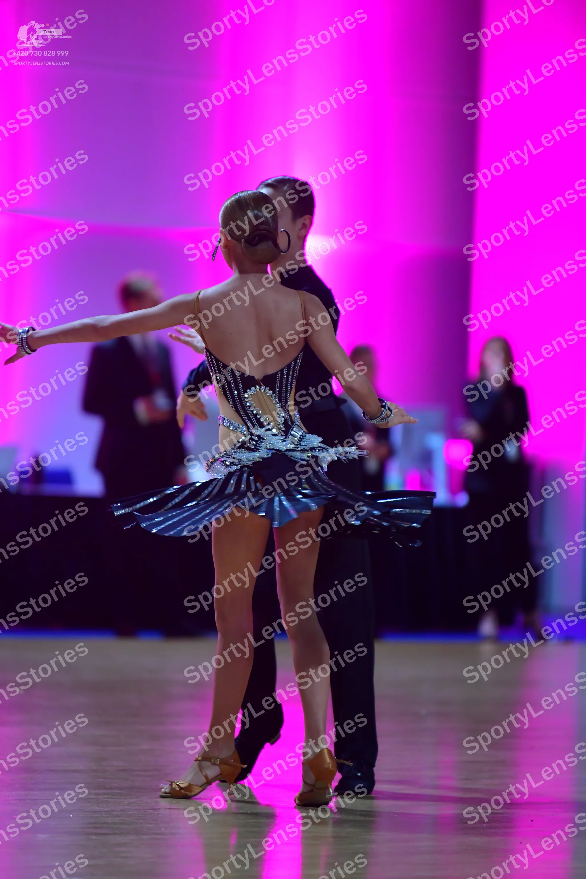 Dancesport competitor: Female dancer: black Latin dress with gold and silver sequined patterns on the b