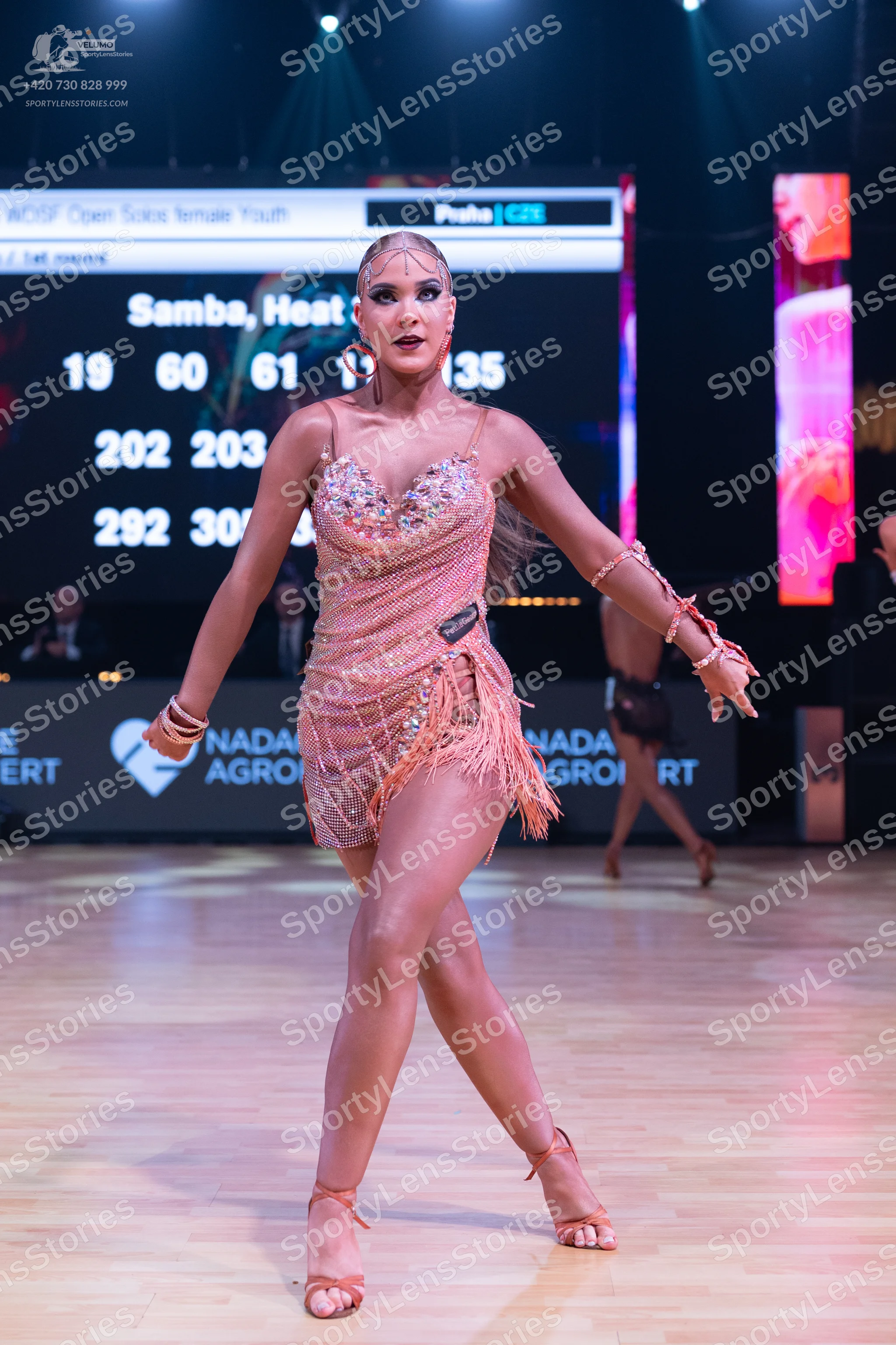 Dancesport competitor: Female dancer in foreground: peach-colored latin dress with sequins, beads, and