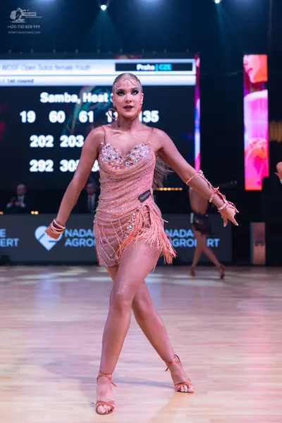 Dancesport competitor: Female dancer in foreground: peach-colored latin dress with sequins, beads, and 