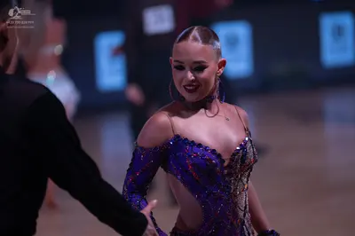 Dancesport competitor: Female dancer: purple Latin dance dress heavily embellished with sequins and rhi