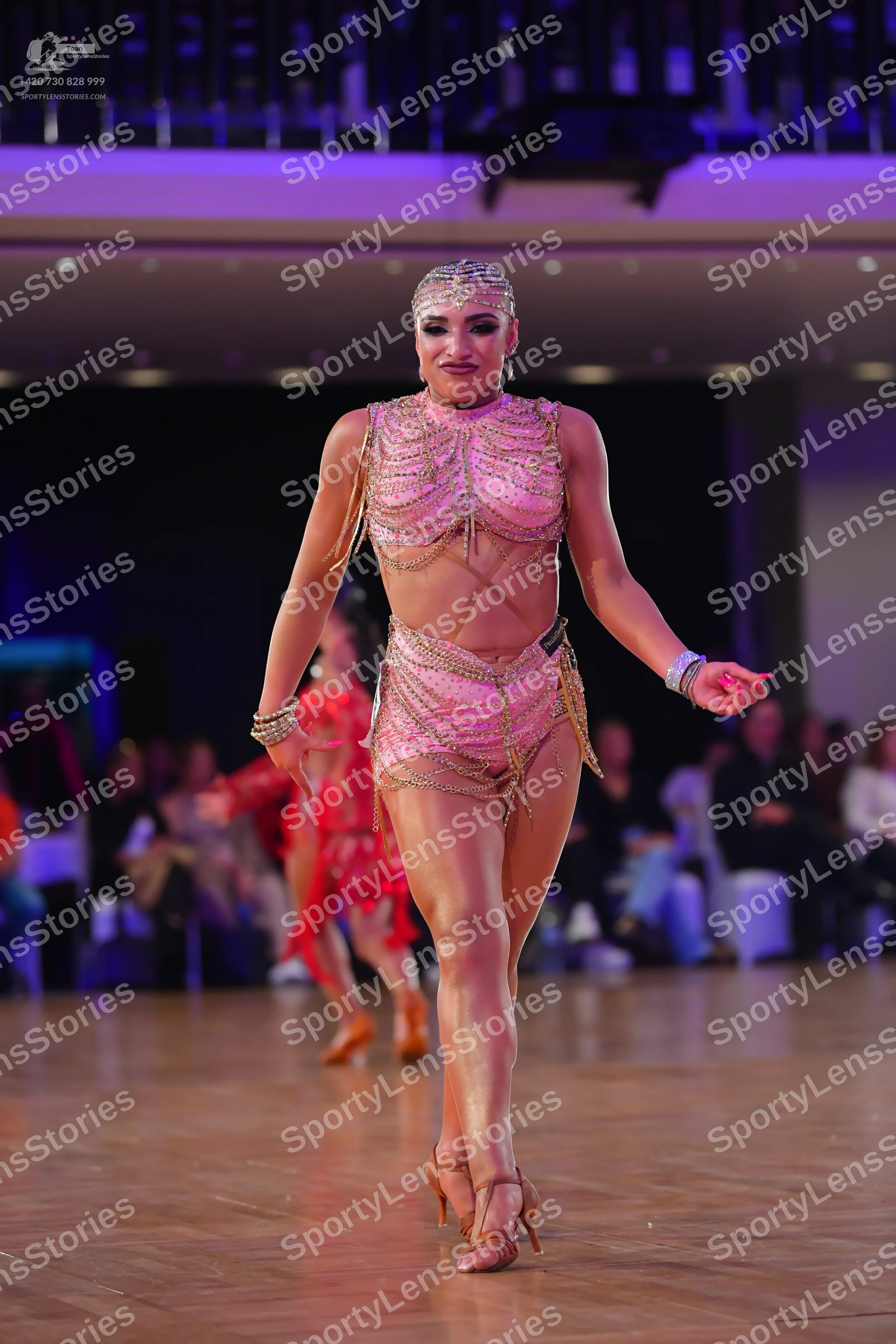 Dancesport competitor: Female dancer in foreground: champagne-colored two-piece latin costume featuring