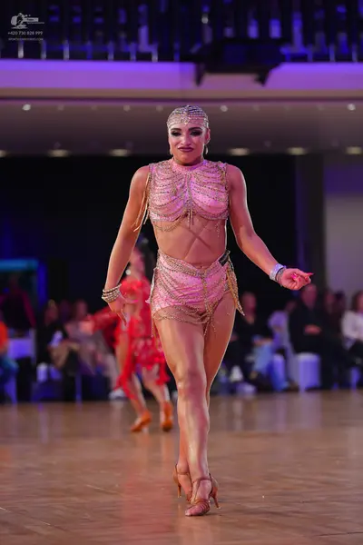 Dancesport competitor: Female dancer in foreground: champagne-colored two-piece latin costume featuring