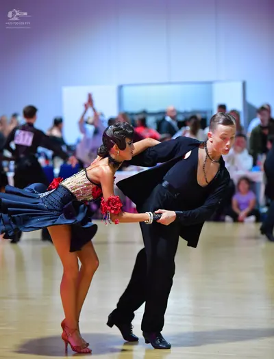 Dancesport competitor: Male dancer: black suit with a black shirt and a dark beaded necklace