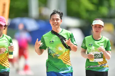 Marathon runner #220: Runner 1: green and yellow jersey, black shorts, pink hat