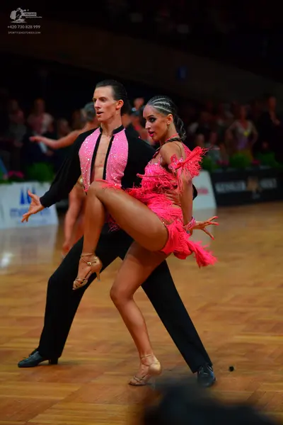 Dancesport competitor: Male dancer: black Latin dance shirt with a large pink front panel and black tro