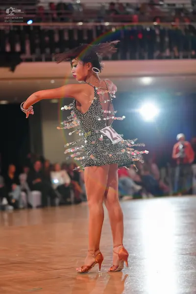 Dancesport competitor: Female dancer: dark-colored, sequined latin dress with large, round, shiny decor
