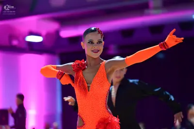 Dancesport competitor: Female dancer: bright orange/coral Latin dance leotard with small sequins and la