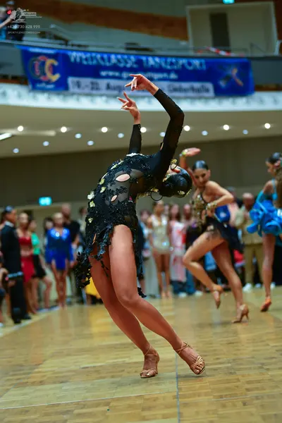 Dancesport competitor: Female dancer 1: black long-sleeved latin dress with cutouts and sequin embellis