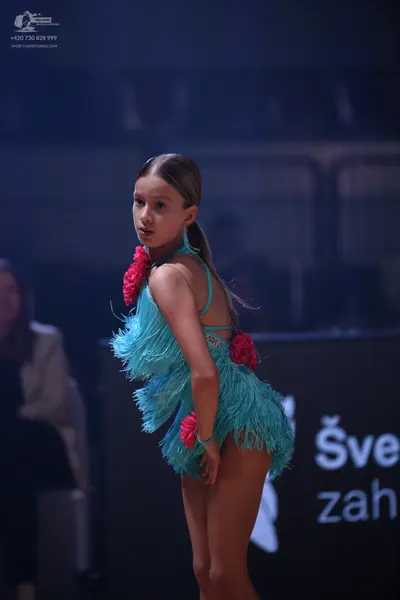 Dancesport competitor: Female dancer: light blue Latin dress with long fringe and pink flower accents o