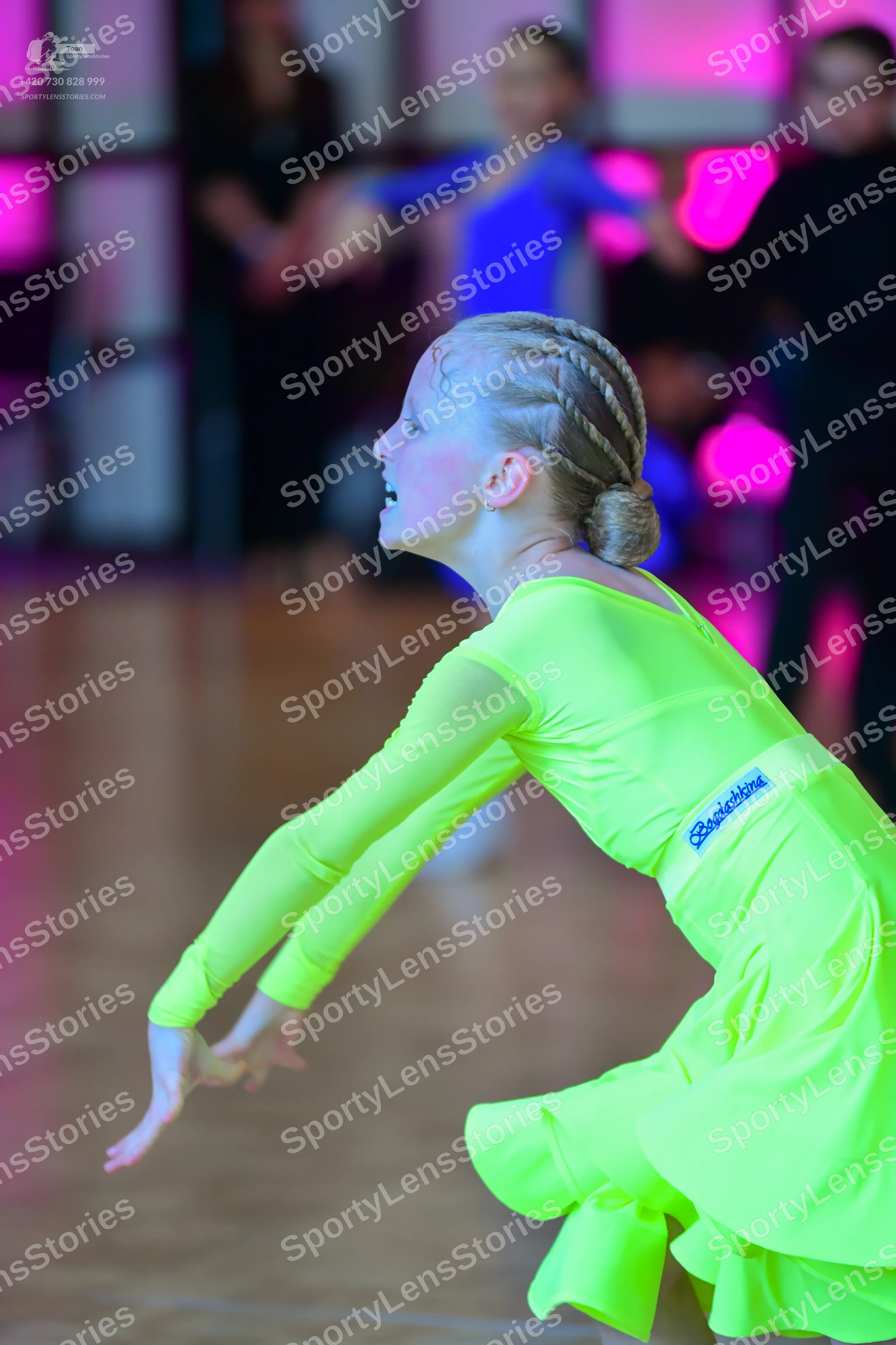 Dancesport competitor: Female dancer in foreground: lime green long-sleeved Latin dress with a flared s