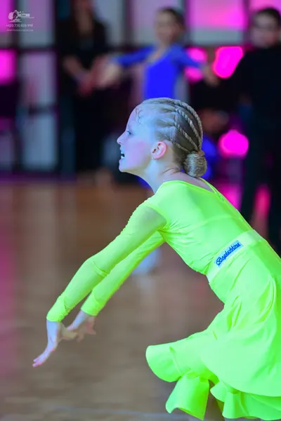 Dancesport competitor: Female dancer in foreground: lime green long-sleeved Latin dress with a flared s