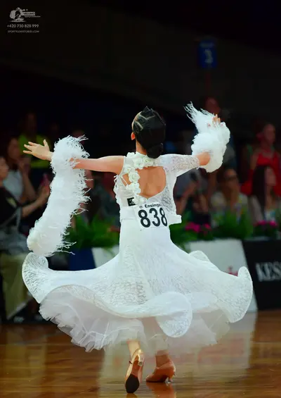 Dancesport competitor: Female dancer: white ballroom dress with lace, a voluminous skirt, and large whi