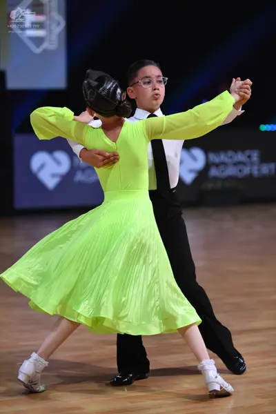 Dancesport competitor: Female dancer: lime green long-sleeved dress with a flowing, pleated skirt and w