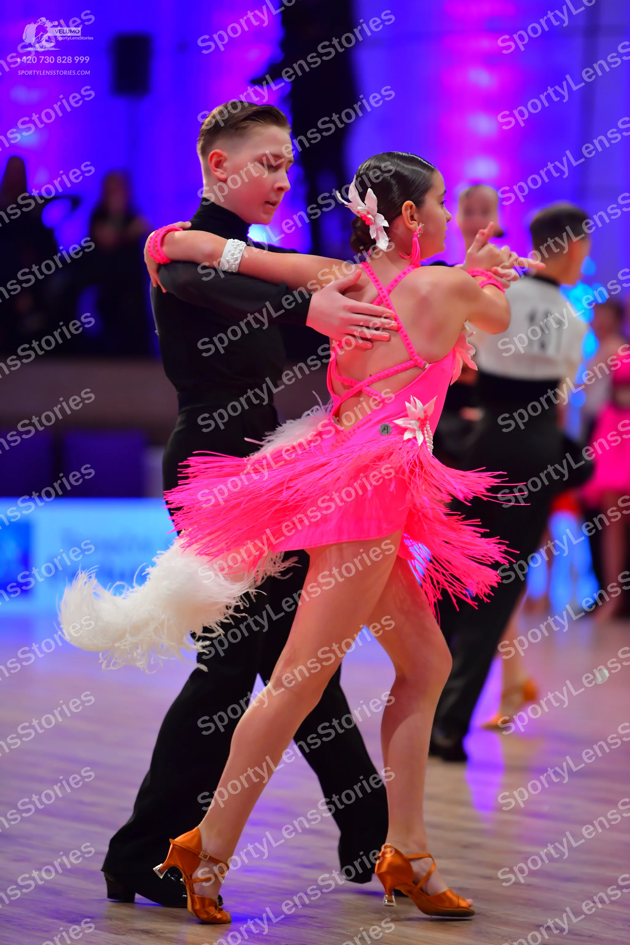 Dancesport competitor: Female dancer: pink latin dress with fringe and a white flower accessory