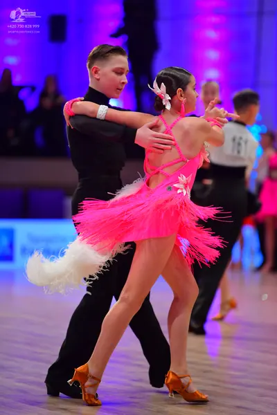 Dancesport competitor: Female dancer: pink latin dress with fringe and a white flower accessory