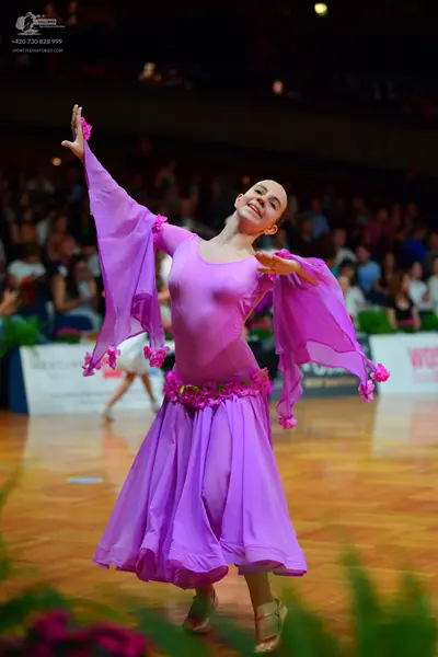 Dancesport competitor: Female dancer in foreground: light purple latin dance dress with long flowing sl