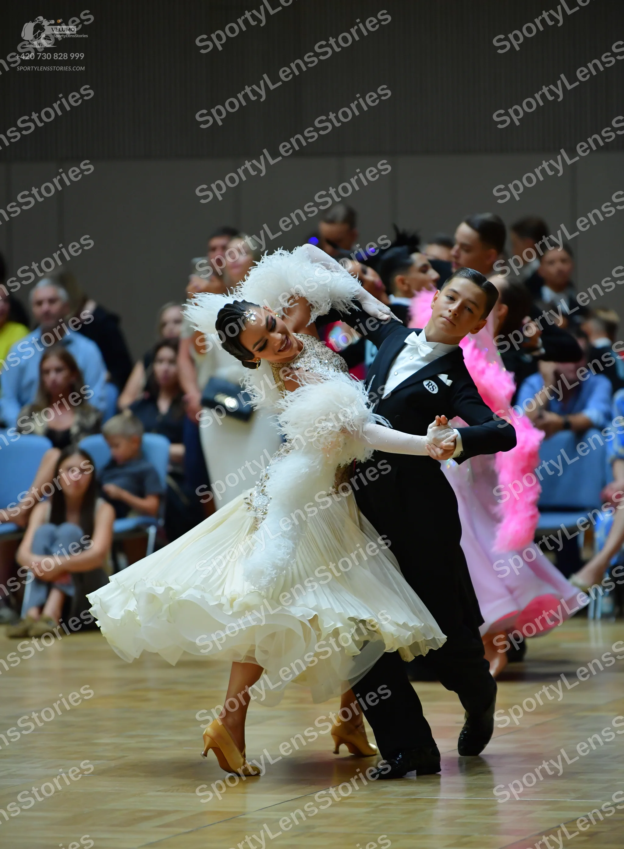 Dancesport competitor: Female dancer: white ballroom dress with a voluminous, layered ruffled skirt and
