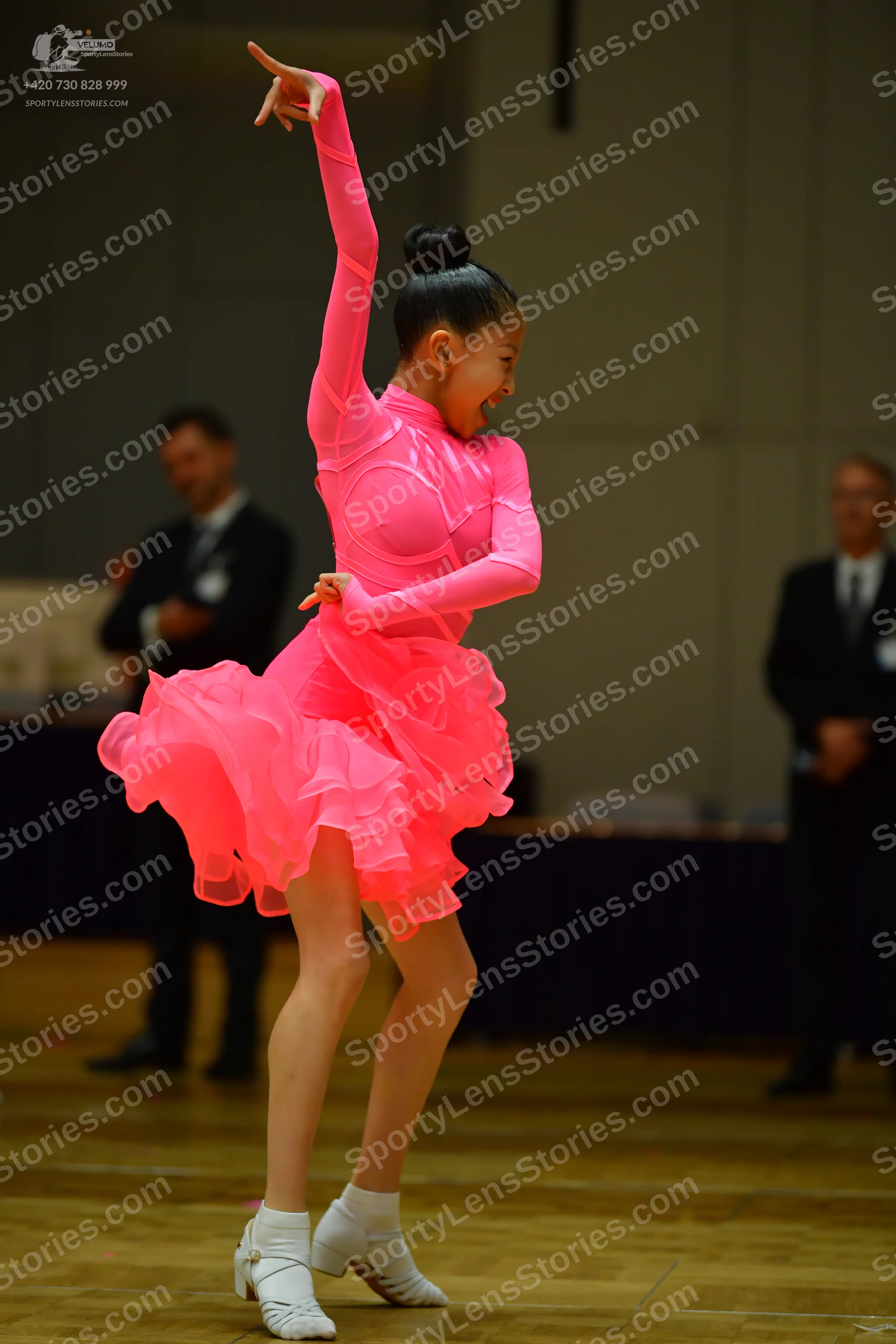 Dancesport competitor: Female dancer: bright pink long-sleeved Latin dance dress with a ruffled skirt