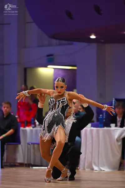Dancesport competitor: Female dancer: black Latin dress with silver sequins and silver fringe, and larg