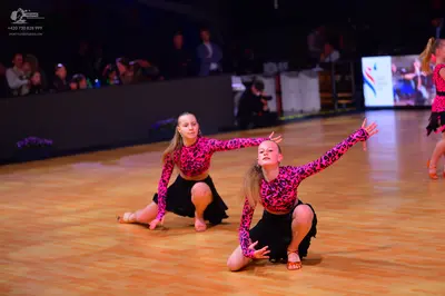 Dancesport competitor: Female dancers: pink and black patterned long-sleeve tops with black skirts