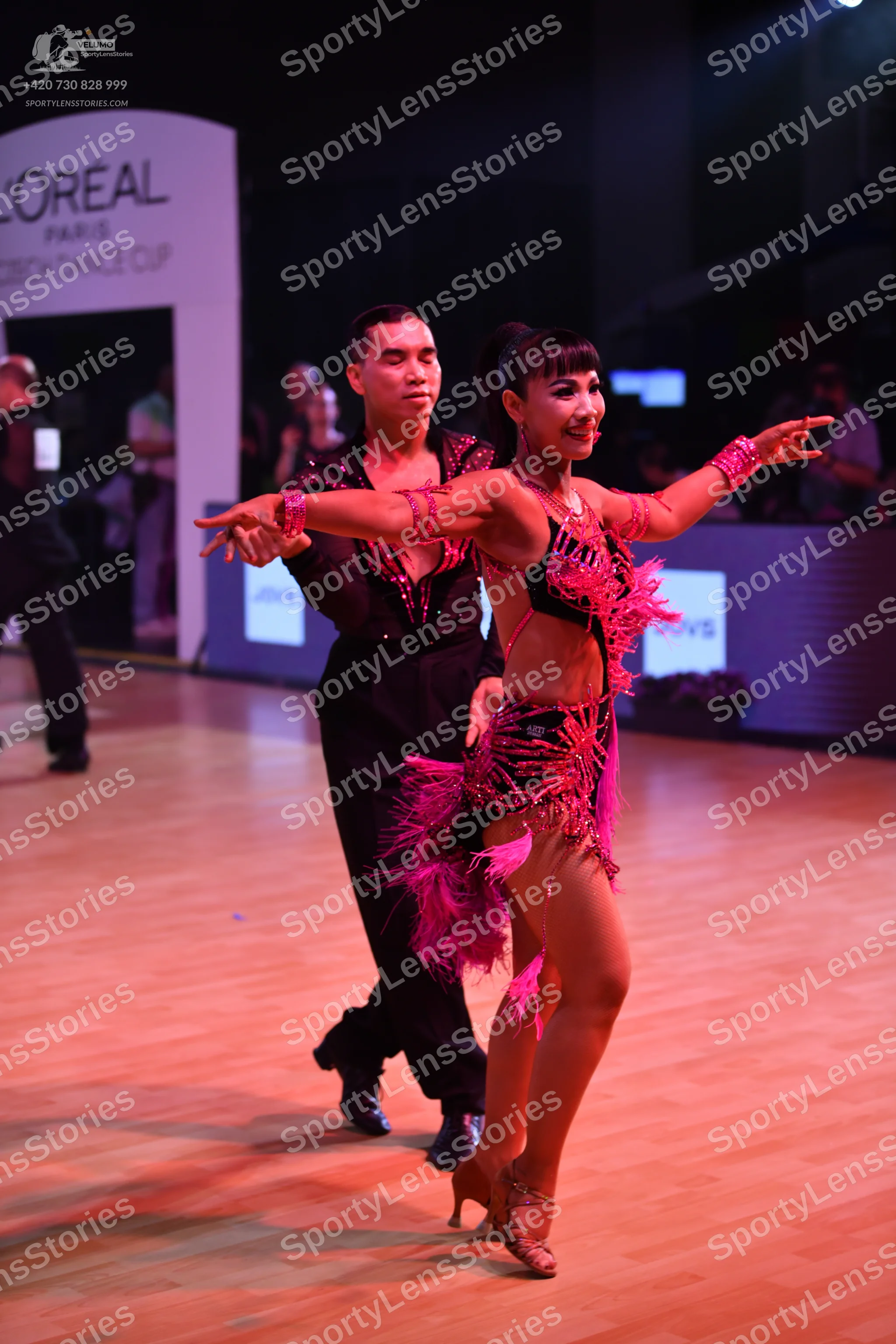 Dancesport competitor: Male dancer: black long-sleeved shirt with pink/red sequin embellishments and bl