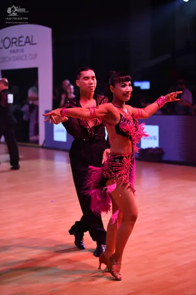Dancesport competitor: Male dancer: black long-sleeved shirt with pink/red sequin embellishments and bl