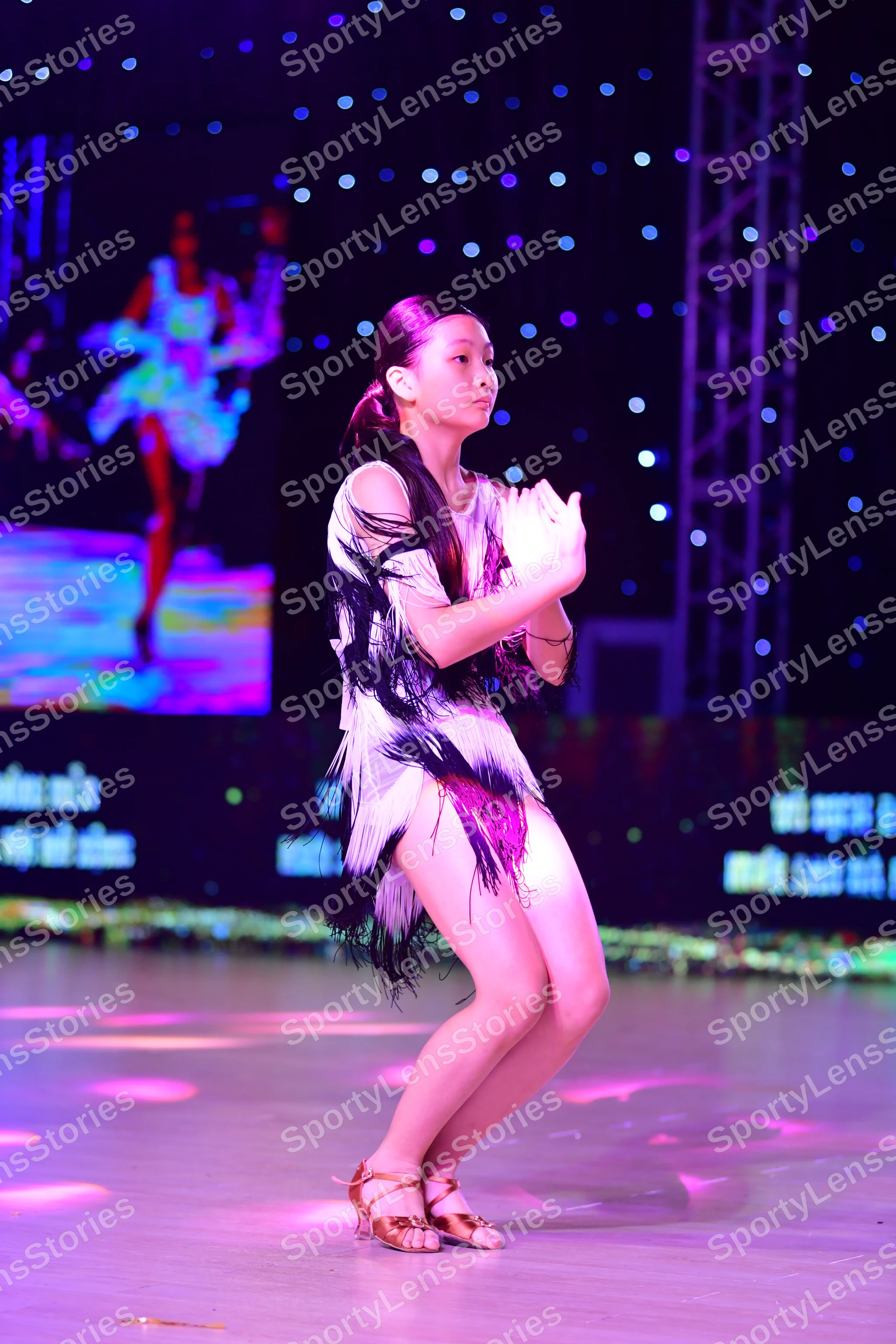 Dancesport competitor: Female (Lead)**: White latin dress with black fringe, halter neck, plunging neck