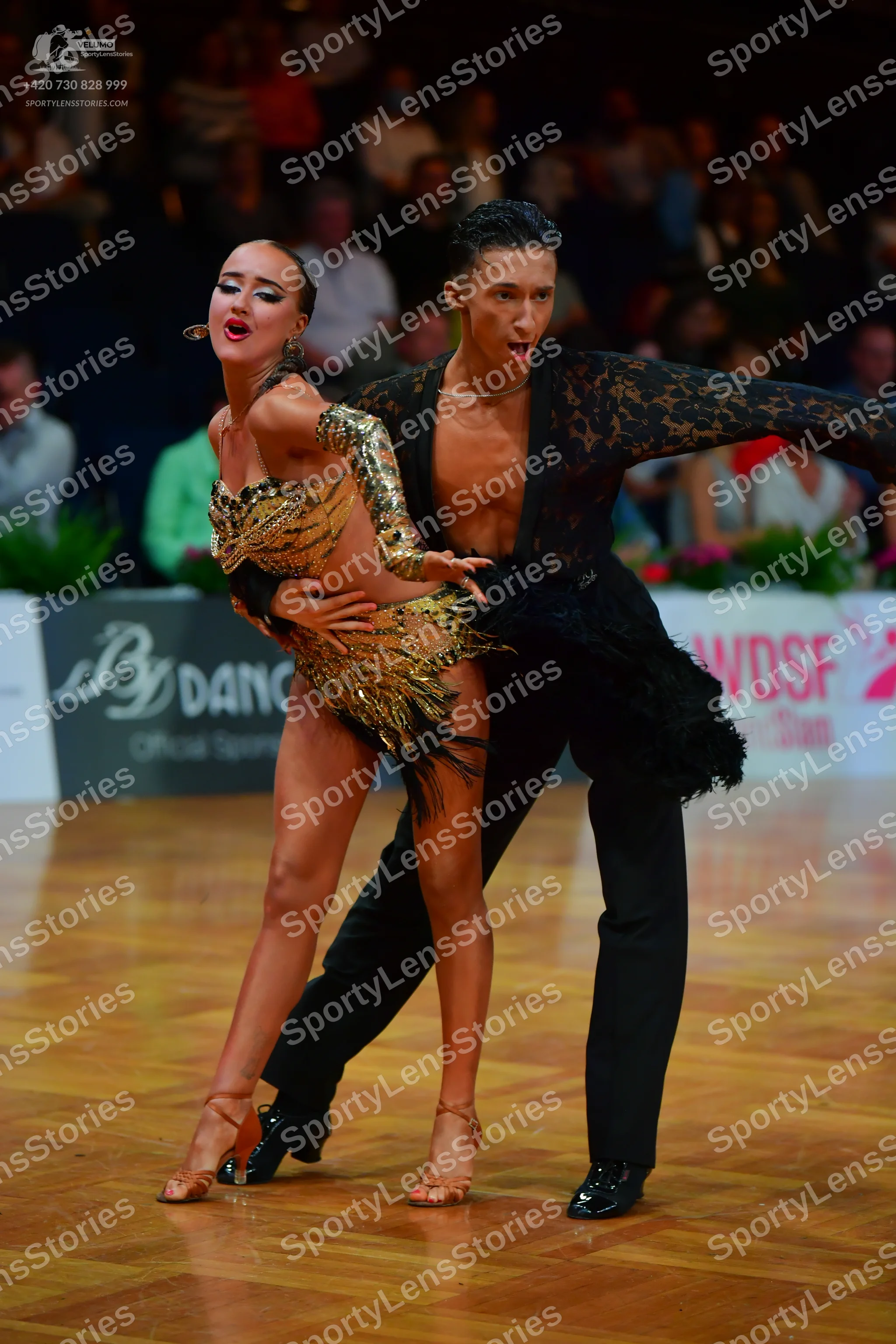 Dancesport competitor: Female dancer: gold latin dress with heavy sequins and fringe, large earrings, a