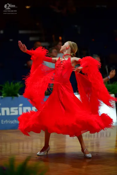 Dancesport competitor: Female dancer: red latin dress with long feathery/fringed sleeves and a matching