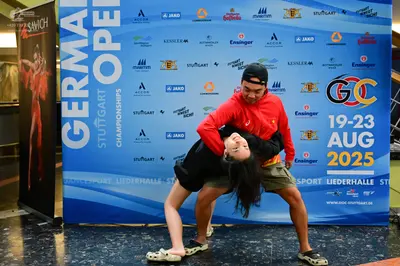 Dancesport competitor: Male dancer: red long-sleeved hoodie, khaki shorts, black baseball cap, and whit