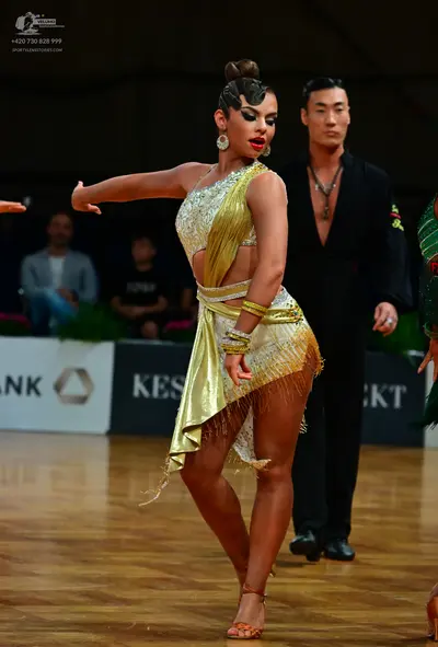 Dancesport competitor: Female dancer: gold sequined latin dance outfit with fringe, large round earring