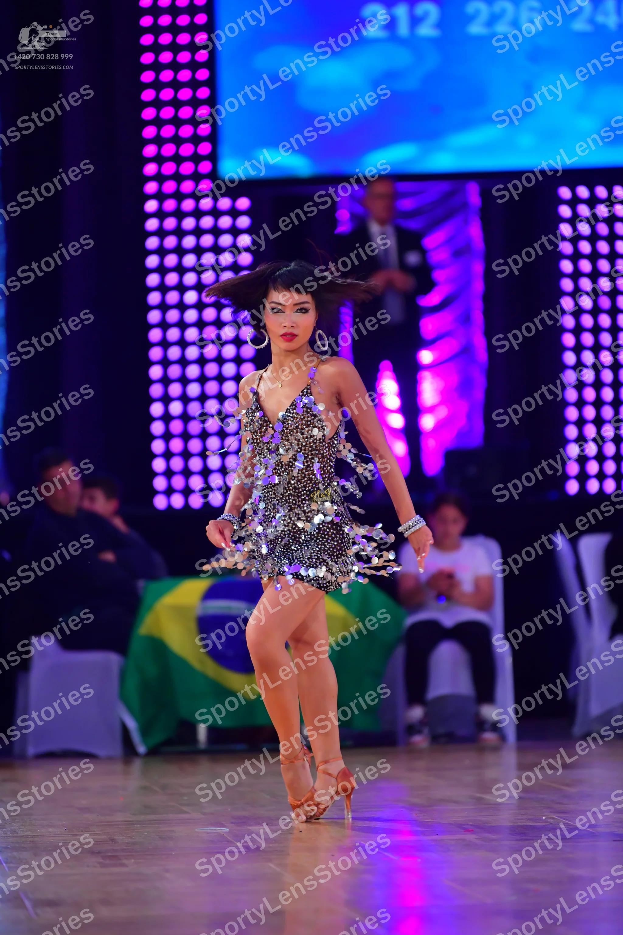 Dancesport competitor: Female dancer: short, dark latin dance dress embellished with silver sequins and