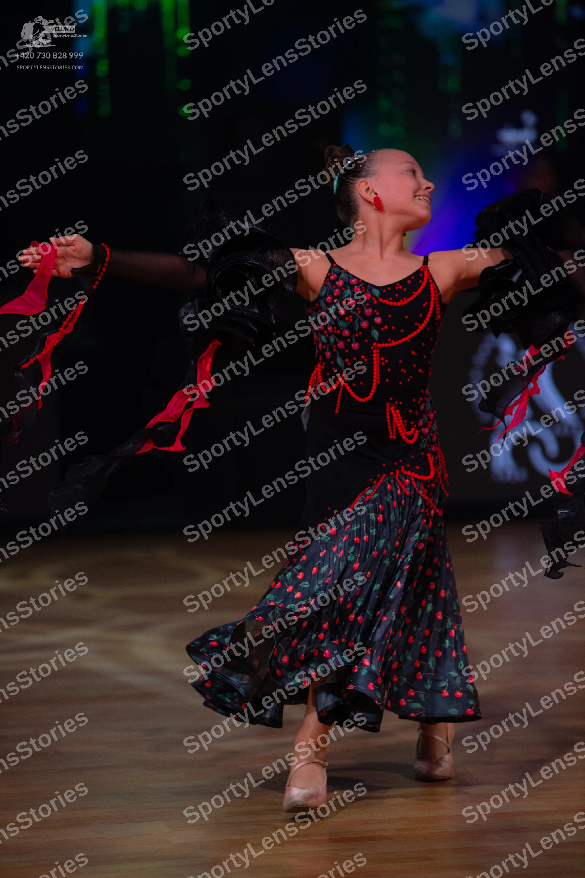 Dancesport competitor: Female dancer: black Latin dress with a red pattern, featuring thin straps, red