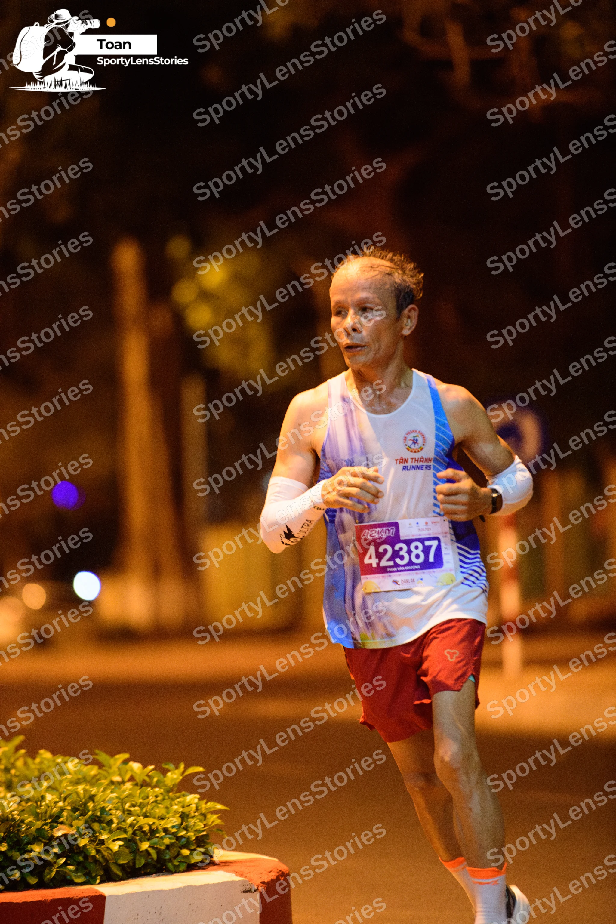 Marathon runner #42387: Runner 1: light blue and white patterned tank top, maroon shorts, white arm slee