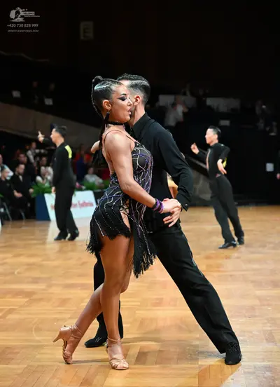 Dancesport competitor: Central female dancer: black sequin Latin dress with black fringe, black choker,