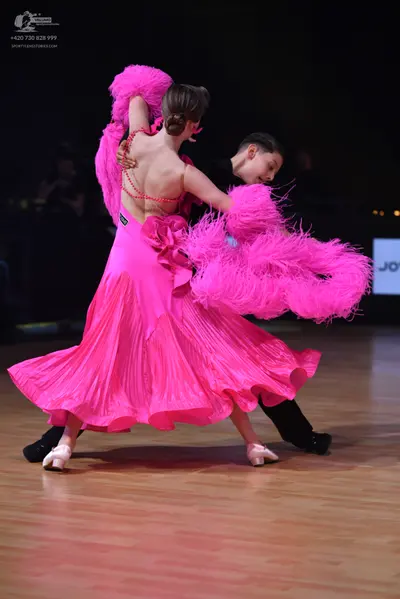 Dancesport competitor: Female dancer: bright pink ballroom dress with a full, pleated skirt, backless d