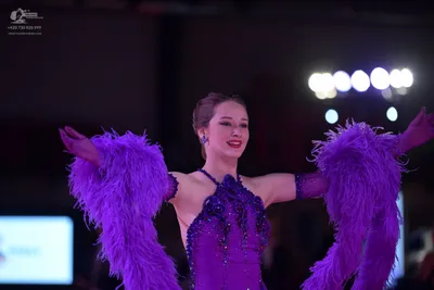 Dancesport competitor: Female dancer: purple latin dress with sequins and large, voluminous purple feat