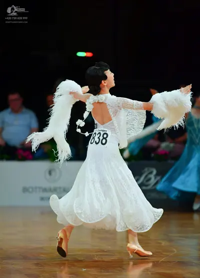 Dancesport competitor: Female dancer: white lace ballgown with long sleeves and large white fluffy feat