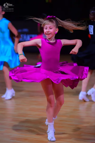 Dancesport competitor: Central dancer: bright pink sleeveless dress with a wide, flared skirt made of s