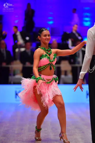 Dancesport competitor: Female dancer: pink latin dress with green beaded decorations and fringe