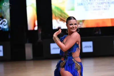 Dancesport competitor: Female dancer: blue latin dress with blue fringe, gold sequins, and nude mesh